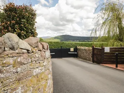 a stone wall with a gate and a road at Swallows Nest in Carlisle