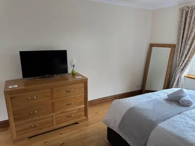 a bedroom with a bed and a dresser with a television at The Haven in Keswick