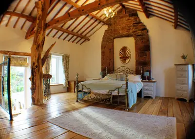 a bedroom with a bed and a stone wall at Romantic Quirky Cottage with private garden and parking in Beckermet