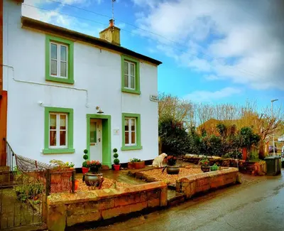 a white house with green windows and a yard at Romantic Quirky Cottage with private garden and parking in Beckermet