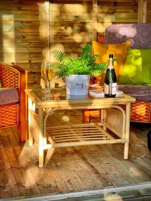 a wooden table with a bottle of wine and a plant at Romantic Quirky Cottage with private garden and parking in Beckermet