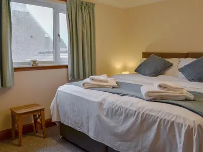 a bedroom with a bed with towels on it at Hawthorn Cottage in Stranraer