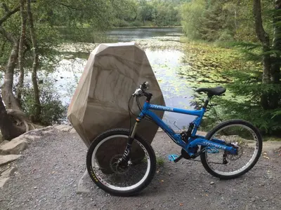 a bike is parked next to a river at Woodburn Lodges in Dumfries