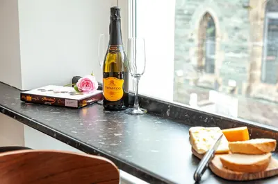 a bottle of wine sitting on a counter with bread and cheese at Carlton 2 a large modern Keswick appt with parking in Keswick