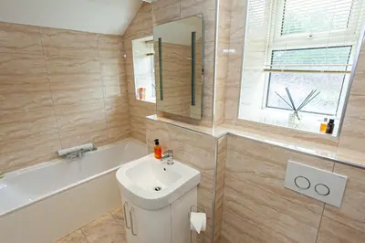 a bathroom with a sink and a tub and a mirror at Carlton 2 a large modern Keswick appt with parking in Keswick