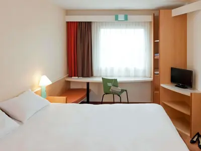 a hotel room with a bed and a desk and a window at ibis Carlisle City Centre in Carlisle