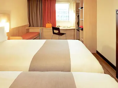 a hotel room with a bed and a chair at ibis Carlisle City Centre in Carlisle