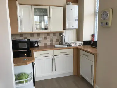 a small kitchen with white cabinets and a microwave at Home with a view in Moffat