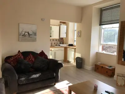 a living room with a couch and a kitchen at Home with a view in Moffat