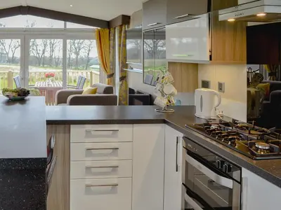 a kitchen with white cabinets and a stove top oven at Skylark Lodge in Westward