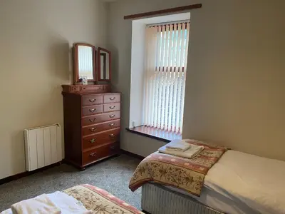 a bedroom with a bed and a dresser and a mirror at Welltrees Apartments 8 Dailly Road in Maybole