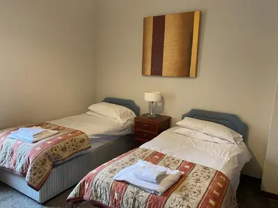 two beds in a hotel room with towels on them at Welltrees Apartments 8 Dailly Road in Maybole