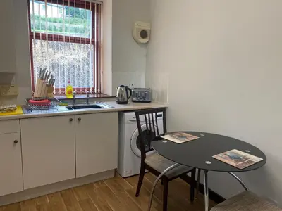 a small kitchen with a table and a sink at Welltrees Apartments 8 Dailly Road in Maybole