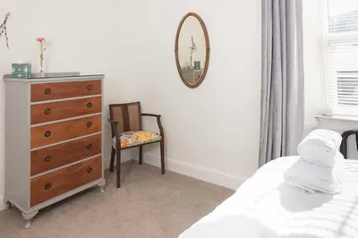 a bedroom with a dresser and a chair and a mirror at Maxwelston Farmhouse in Girvan