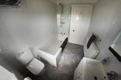 a white bathroom with a tub and a toilet and a sink at Ayr Beach View Apartment in Ayr
