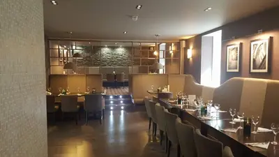 a restaurant with a bar with tables and chairs at The Fairburn Hotel in Mauchline