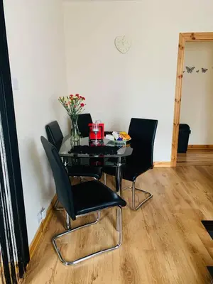 a dining room table with black chairs and a vase of flowers at Private Apartment in Dumfries
