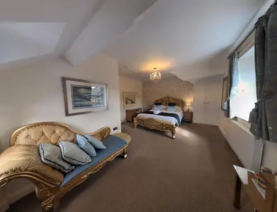 a bedroom with a king sized bed and a couch at Allerdale Guest House in Keswick