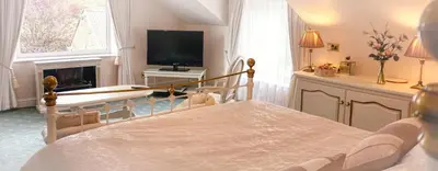 a bedroom with a bed and a tv and a fireplace at Bessiestown Country Guesthouse in Carlisle