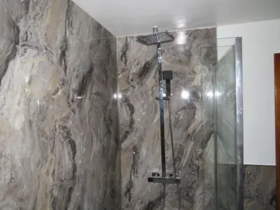 a bathroom with a shower with a stone wall at Criffel Cottage in Dumfries