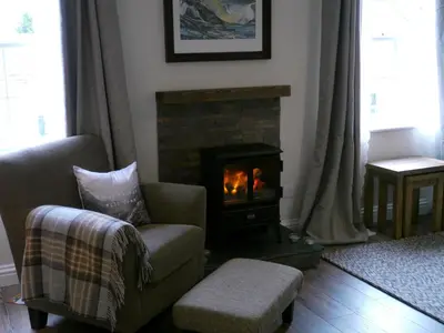 a living room with a chair and a fireplace at Scafell View Apartment, Wasdale, Lake District, Cumbria in Nether Wasdale
