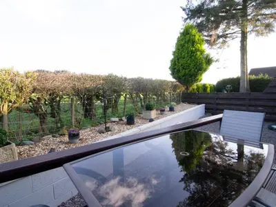 a glass table with a view of a garden at Kestrel Lodge in Beeswing