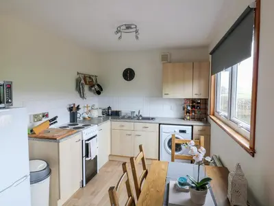 a kitchen with a wooden table and a kitchen with white appliances at Kestrel Lodge in Beeswing