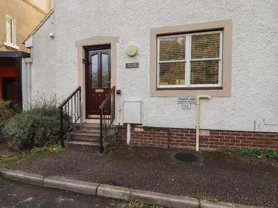 a house with a door and stairs in front of it at Riverside Cottage in Cockermouth