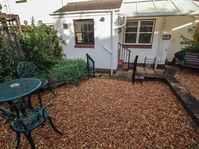 a patio with a table and chairs in front of a house at Riverside Cottage in Cockermouth