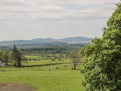 a field of green grass with mountains in the distance at Garden Cottage in Castle Douglas