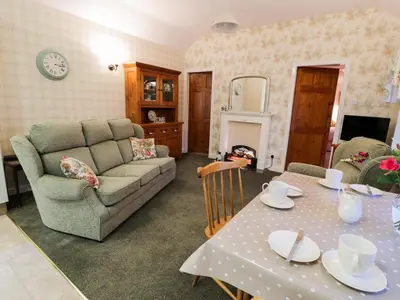 a living room with a couch and a table at Garden Cottage in Castle Douglas