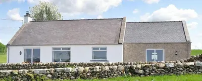 a white house with a stone fence in front of it at Fleet View in Gatehouse of Fleet