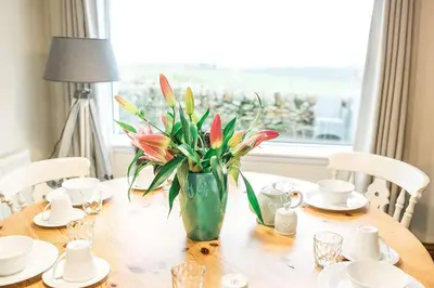 a wooden table with a vase of flowers on it at Fleet View in Gatehouse of Fleet