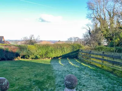 a garden with a fence and a grass yard at Butterhole Cottage in Kelton