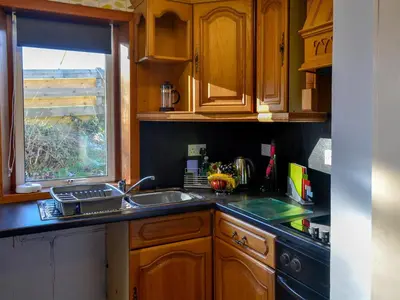 a kitchen with wooden cabinets and a sink and a window at Butterhole Cottage in Kelton