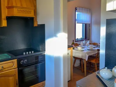 a kitchen with a stove and a dining room at Butterhole Cottage in Kelton