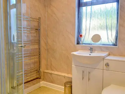 a bathroom with a shower and a sink and a window at Butterhole Cottage in Kelton
