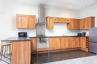 a kitchen with wooden cabinets and a stove at Granary Suite No3 - Donnini Apartments in Ayr
