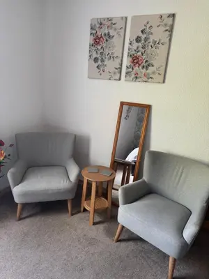 a room with two chairs and a table and a mirror at Prince Charlie's Cottage in Gretna Green