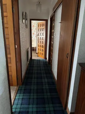 a hallway with a carpeted floor and wooden doors at Prince Charlie's Cottage in Gretna Green