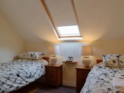 a attic bedroom with two beds and a skylight at Ghillie Cottage in Cockermouth