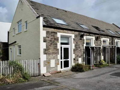 a brick house with windows and a fence at Ghillie Cottage in Cockermouth