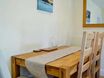 a wooden table with a wine glass on top of it at Ghillie Cottage in Cockermouth