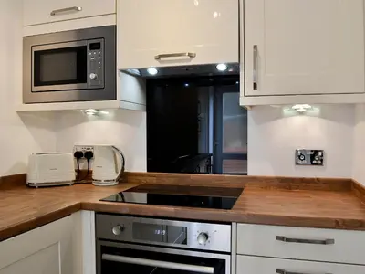 a kitchen with a stove and a microwave at Ghillie Cottage in Cockermouth
