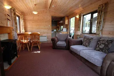 a living room with a couch and chairs and a stove at Fellside Lodge in Keswick