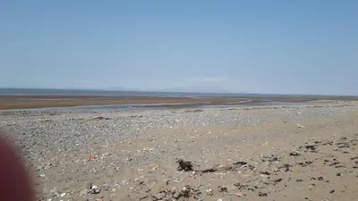 a beach with rocks and water in the distance at 27 The Beeches, Gilcrux, Nr Cockermouth, Cumbria in Gilcrux