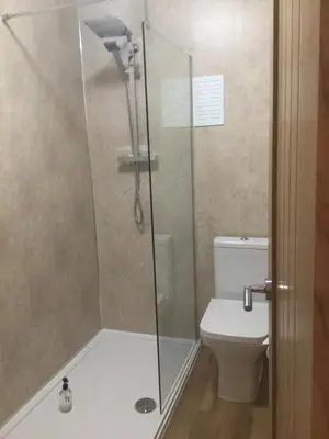 a shower with a glass door next to a toilet at Ravensworth House in Keswick
