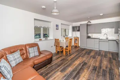 a living room with a couch and a kitchen at Sam's Cottage in Keswick