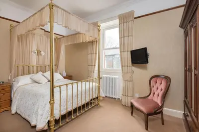 a bedroom with a canopy bed and a chair at Acorn House in Keswick