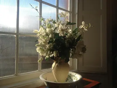 a vase of flowers sitting on a table in front of a window at Acorn House in Keswick
